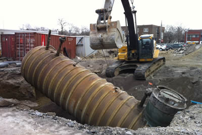 Image of a backhoe lowering container into the ground