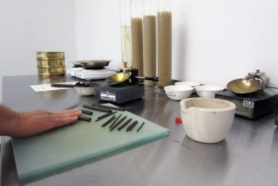 Image of a laboratory table with samples and equipment with a worker conducting test.