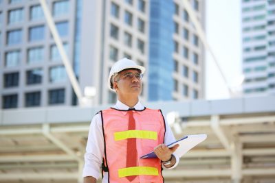 Image of worker in safety gear and a clipboard at a pre-construction site for condition assessment.