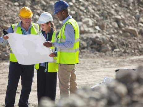 Image of workers with safety gear on a construction site, reviewing plans