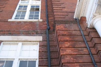 Image of an old brick building and water spouts as part of a building Condition Assessment.